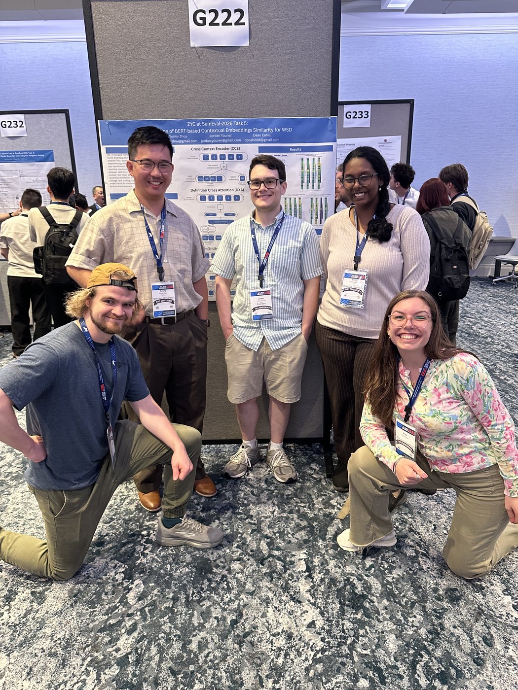 A group of Brandeis attendees kneeling and standing in front of a poster board at the conference.