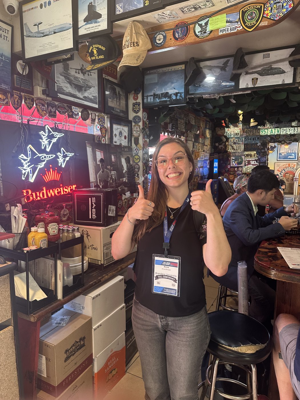 Anna giving a thumbs up inside Kansas City BBQ, surrounded by neon beer signs and memorabilia.
