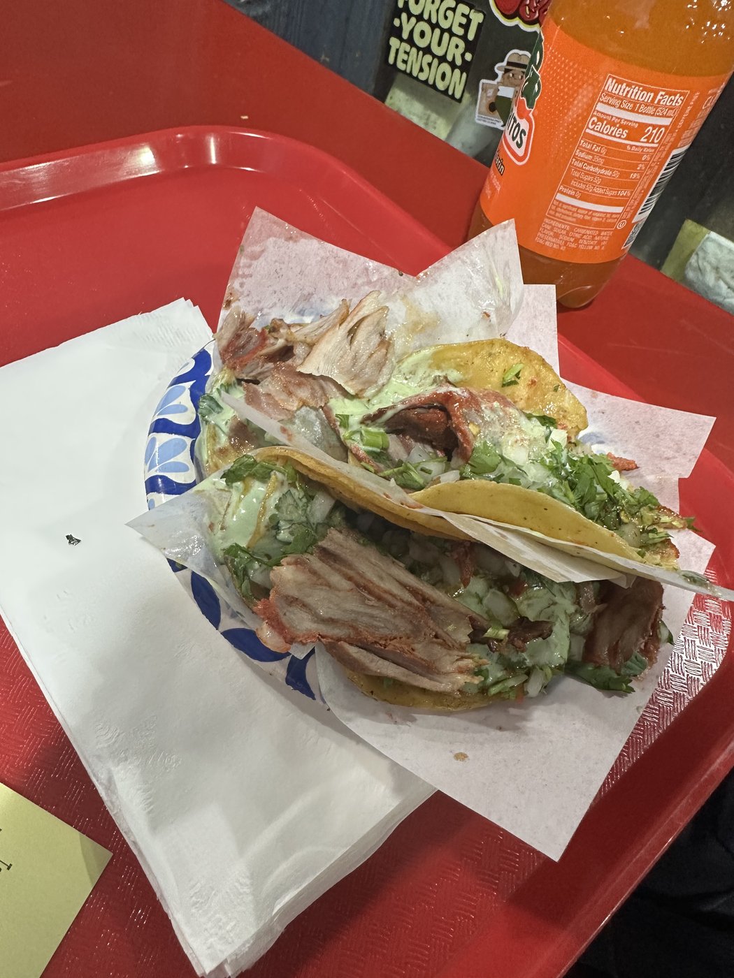 Two adobado street tacos piled with meat, cilantro, and salsa on a red cafeteria tray.