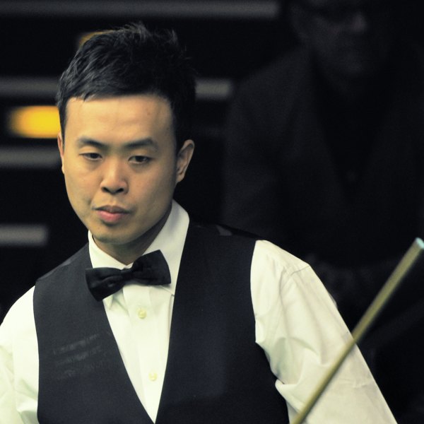 Marco Fu in a black waistcoat and bow tie, holding his cue, at the 2014 German Masters. Photo by Martin Rulsch, CC BY-SA 4.0, via Wikimedia Commons.