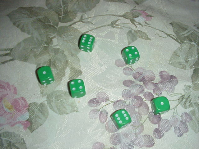 Six green dice scattered on a floral tablecloth. Photo by Shuffdog, public domain, via Wikimedia Commons.