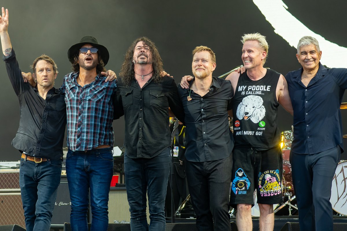 Foo Fighters on stage at Glastonbury 2023, arms around each other. Photo by Raph_PH, CC BY 2.0, via Wikimedia Commons.