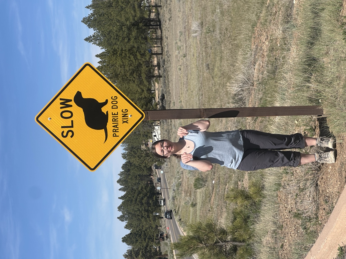 Anna posing beside a 'Slow: Prairie Dog Xing' sign.