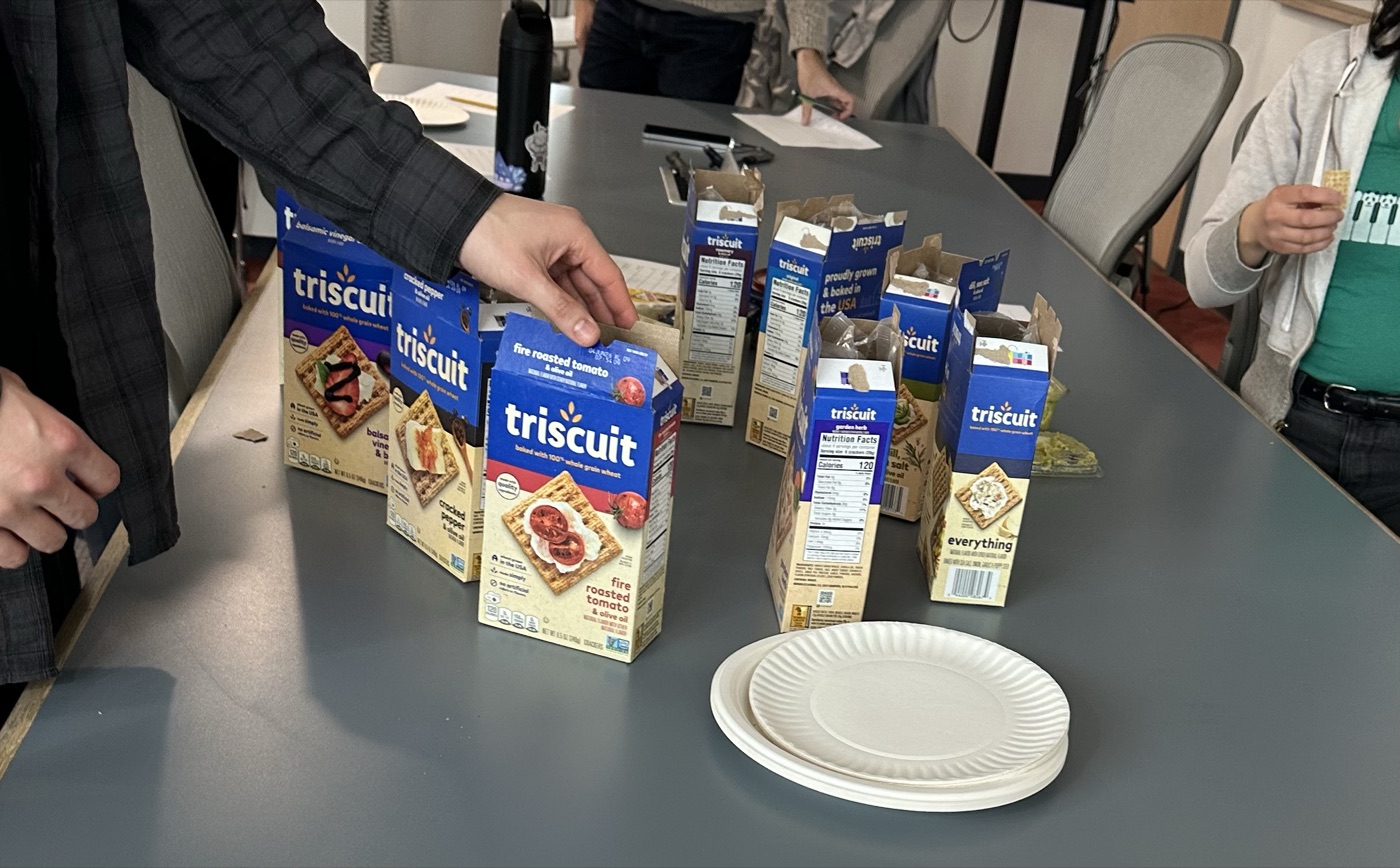 Ten boxes of different Triscuit flavors lined up on a conference table.